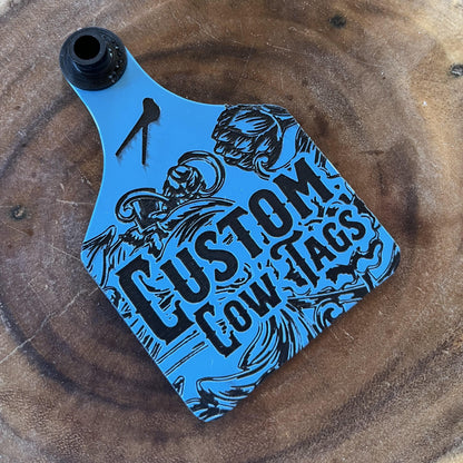 Blue and black 'Custom Cow Tags' product on a wooden surface