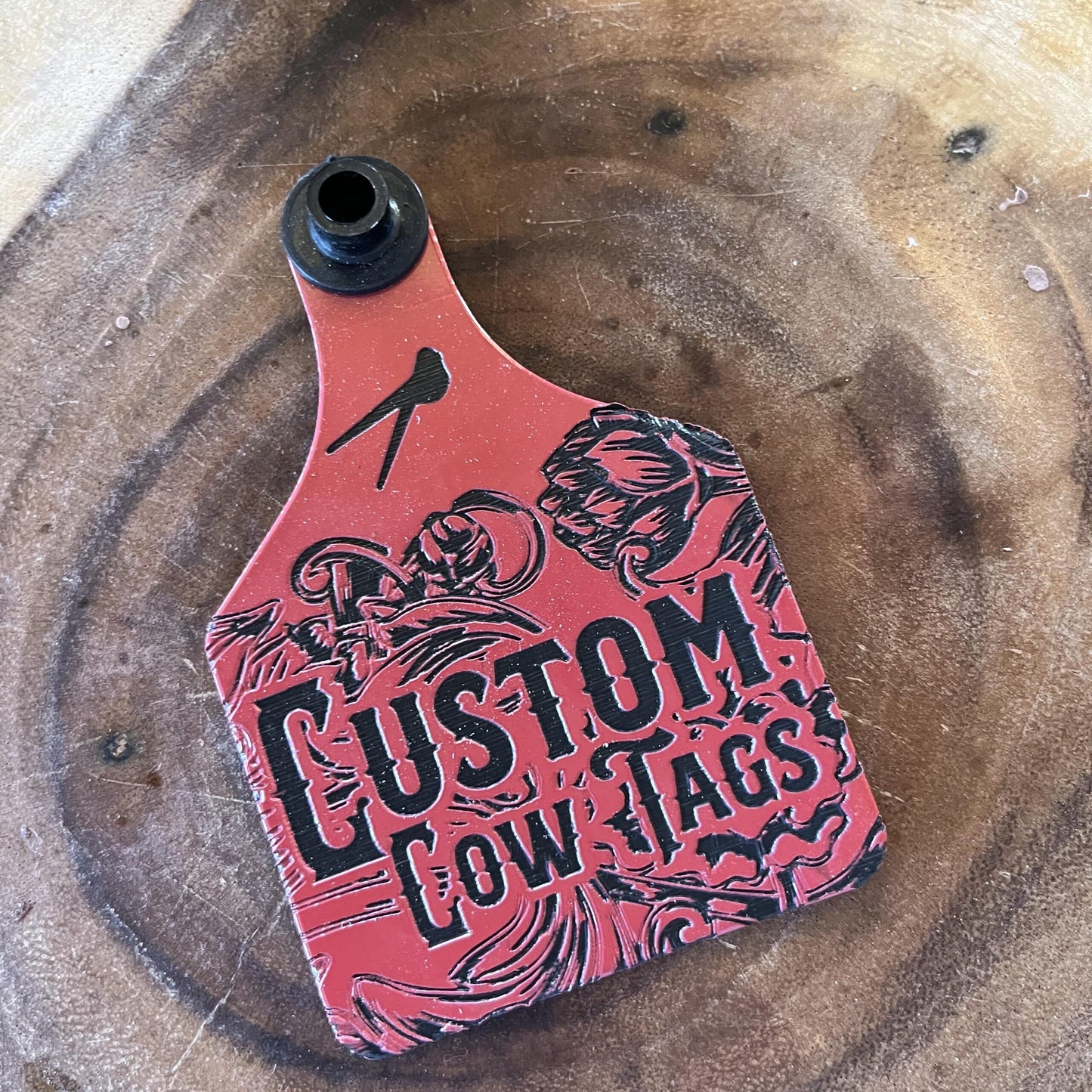 Red and black 'Custom Cow Tags' product on a wooden surface