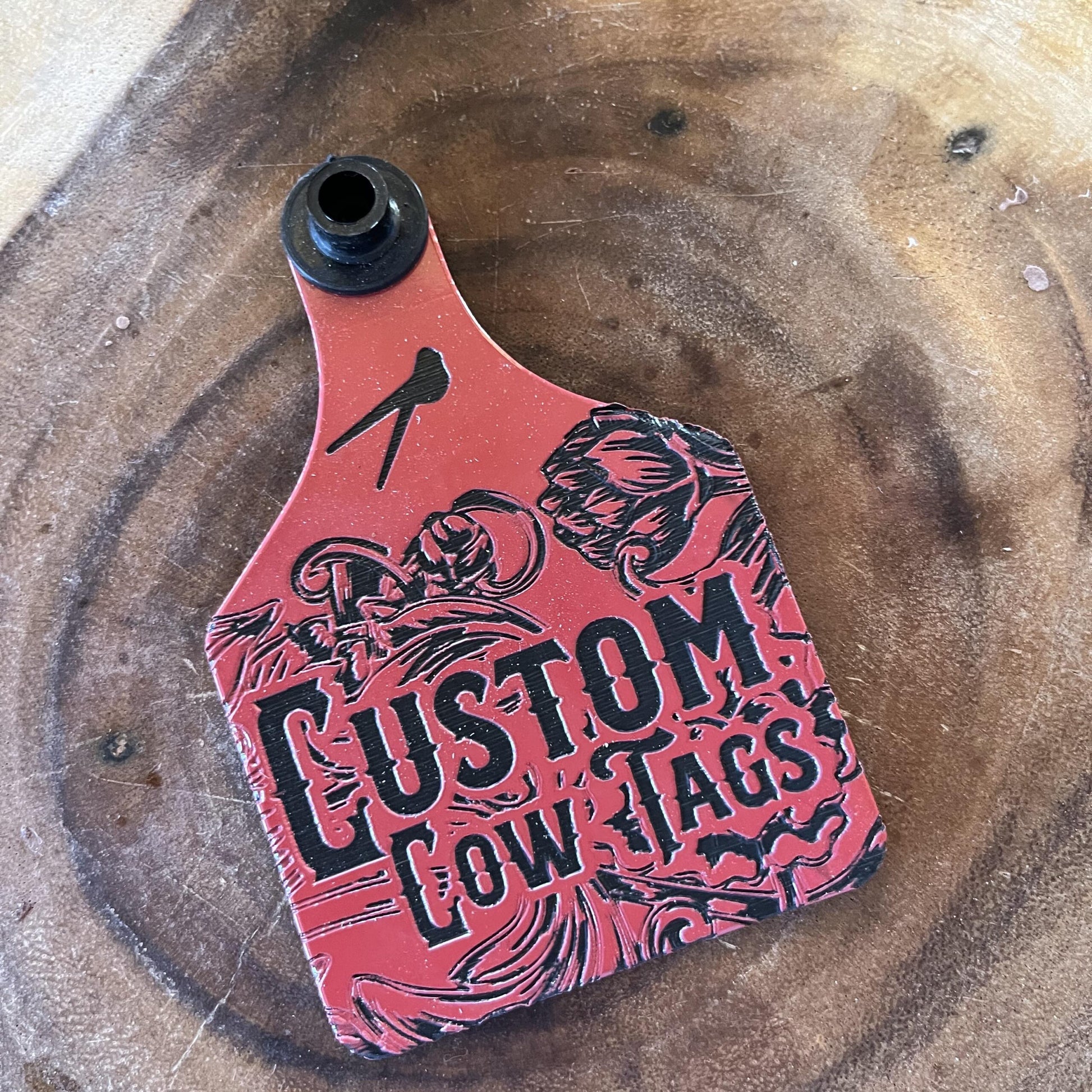 Red and black 'Custom Cow Tags' product on a wooden surface