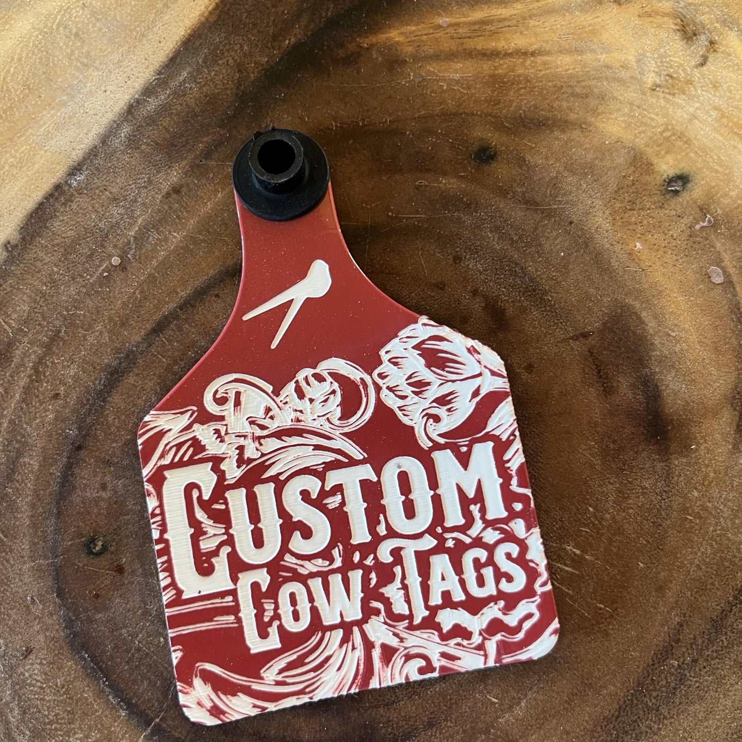 Red and white custom cow tag on a wooden surface