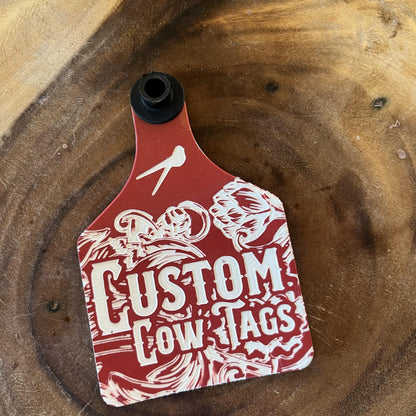 Red and white custom cow tag on a wooden surface