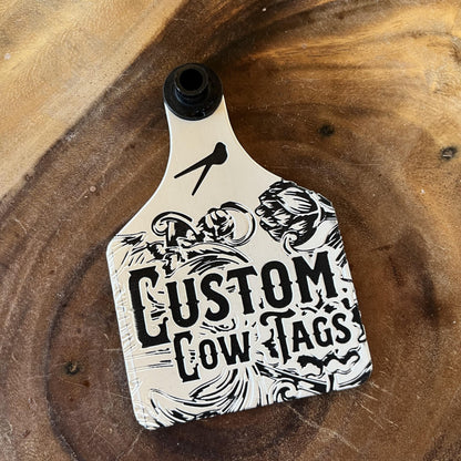 Custom cow tag with black and white design on a wooden surface