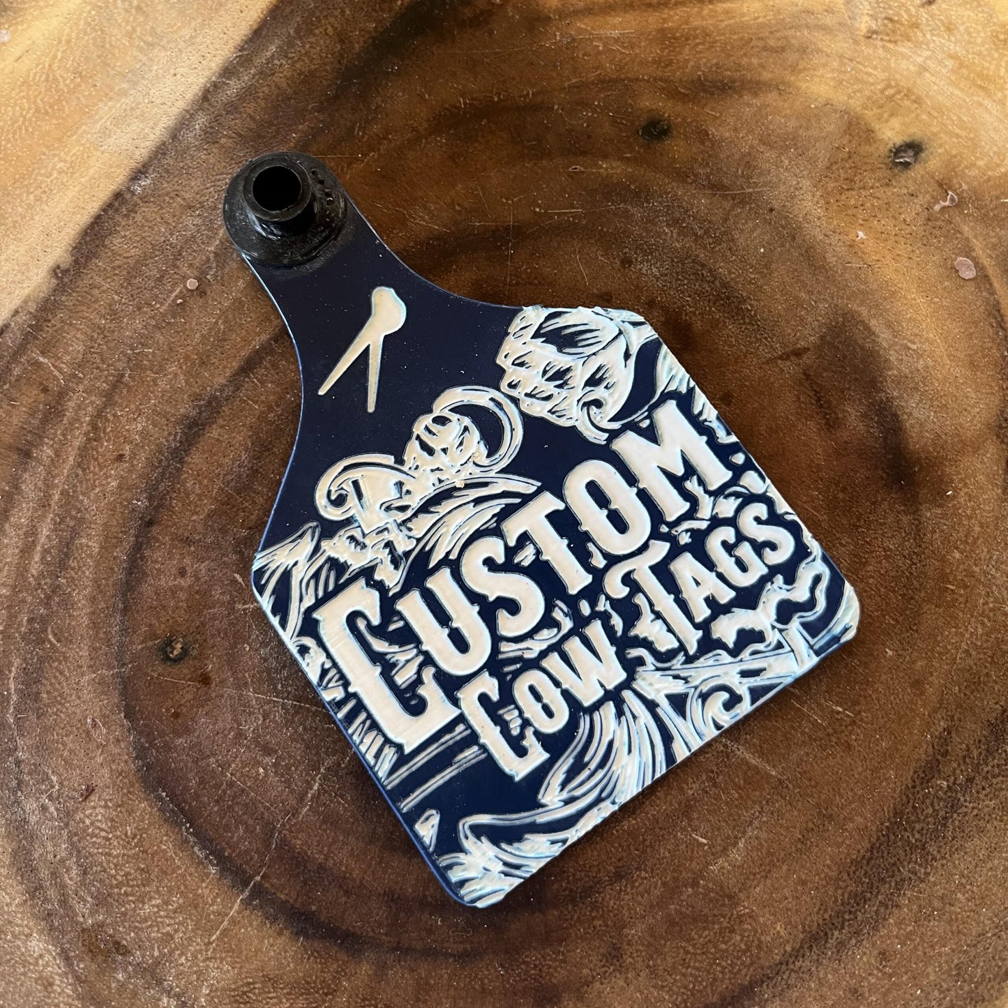 Custom cow tag with branding on a wooden surface
