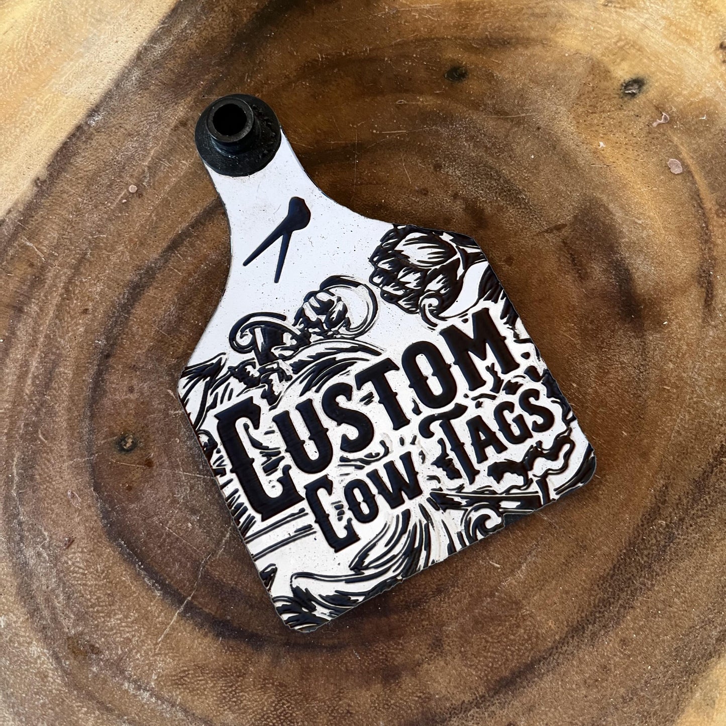 Custom cow tag with black and white design on a wooden surface