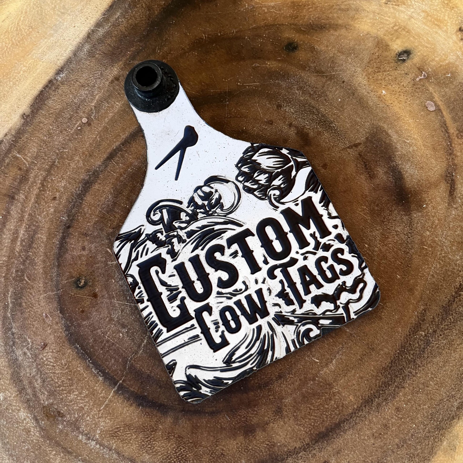 Custom cow tag with black and white design on a wooden surface
