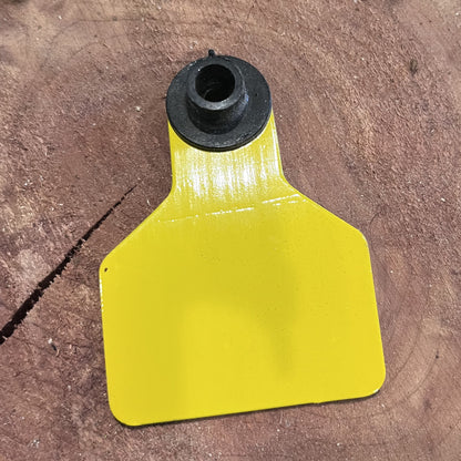Yellow plastic tag with black rubber grommet on a brown surface