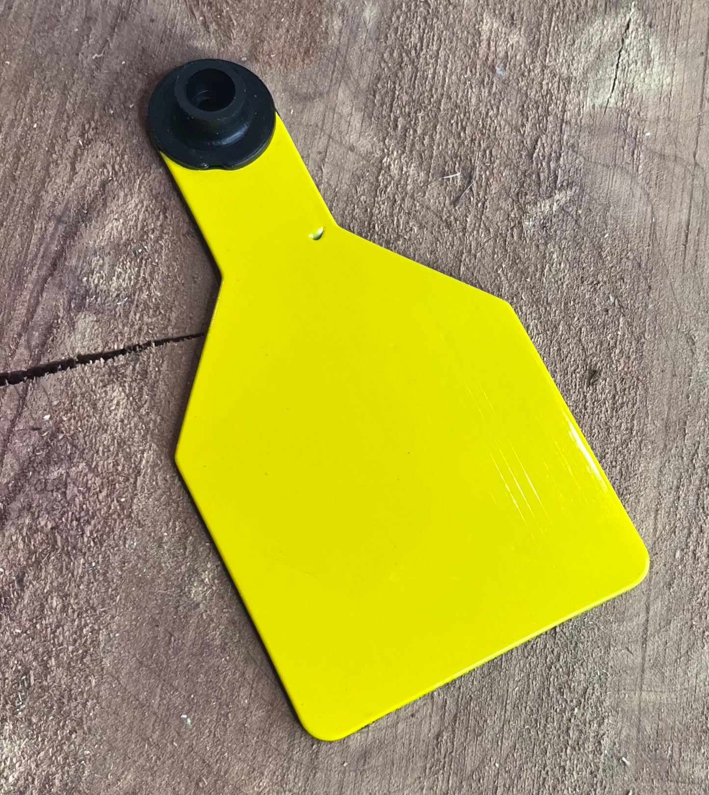 Yellow plastic tag  on a wooden surface