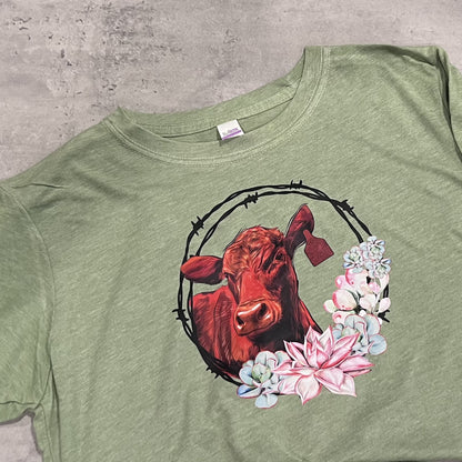 Green t-shirt with a red bull and floral design on a concrete surface